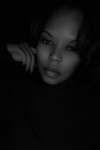 Headshot of April in a dark background with a hand on her cheek.
