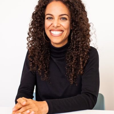 Erika seated at a table with hand folded wearing a black shirt